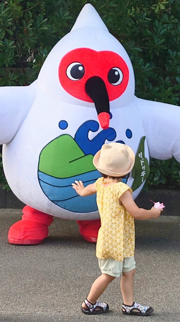 Crested ibis mascot with a kid at Toki-no-mori Park